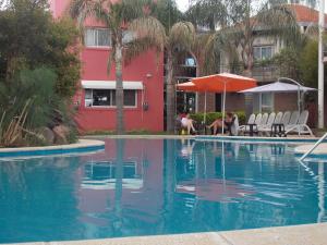 a woman sitting under an umbrella next to a swimming pool at Paraiso Termal in Federación +25 photos
