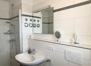 a white bathroom with a sink and a mirror at Haus zur Mole - Morgenstern in Großenbrode