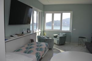 a bedroom with a bed and two chairs and a flat screen tv at CaseMaggi Attico sul Mare, Penthouse on the Sea in Portovenere