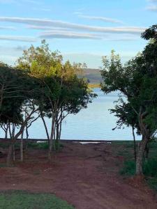 um grupo de árvores em frente a uma massa de água em Casa de temporada no Lago de Furnas-acesso a represa em São José da Barra