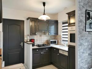 uma cozinha com armários cinzentos e uma porta preta em A 3 min de la plage à Sarzeau em Sarzeau