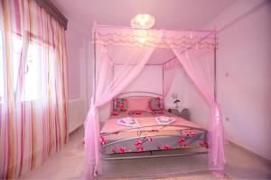 a pink bed with a canopy in a room at Titika House in Nea Vrasna