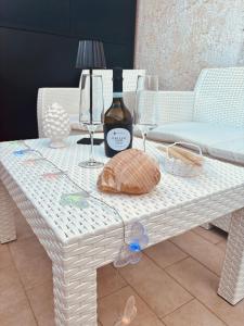 una mesa de mimbre blanca con una botella de vino y copas en Butterflies Home Giardini Naxos, en Schisò