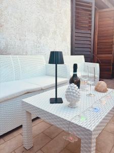 una mesa con una lámpara y una botella de vino. en Butterflies Home Giardini Naxos, en Schisò
