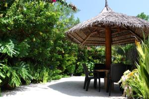 une table et des chaises sous un parasol de paille dans l'établissement Hanifaru Transit Inn, à Dharavandhoo