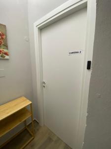 eine weiße Tür mit einem Schild neben einem Tisch. in der Unterkunft La casa nel vicolo Camera 2 in Casale Monferrato