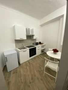 a kitchen with white cabinets and a table and a table and chair at La casa nel vicolo Camera 2 in Casale Monferrato