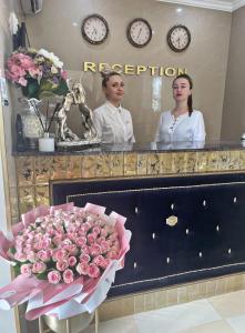 two women standing in front of a mirror with a bouquet of flowers at Diamond Hotel in Chişinău