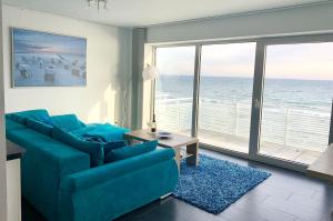 a living room with a blue couch and a view of the ocean at Haus zur Mole - Morgenstern in Großenbrode