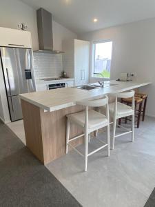 a kitchen with a sink and a counter with chairs at Modern and new house in Taupiri