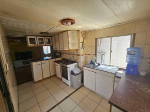 a small kitchen with white appliances and a window at Amplia Casa a 4 cuadras de playa in Los Vilos