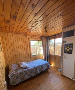 a bedroom with a bed in a wooden room at Amplia Casa a 4 cuadras de playa in Los Vilos