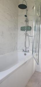 y baño con ducha y bañera blanca. en LONDON EXPERIENCE, en Eltham