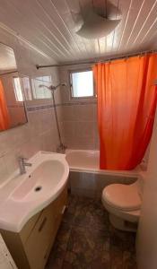 an orange shower curtain in a bathroom with a toilet and sink at Amplia Casa a 4 cuadras de playa in Los Vilos
