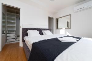 a white bedroom with a large bed and a mirror at Two-level apart with a terrace near the Vltava River in Prague