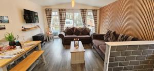 uma sala de estar com um sofá e uma mesa em Tranquil Lodge hot tub and free golf em Swarland