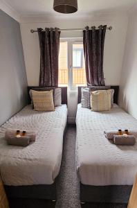 two beds in a room with two windows at Tranquil Lodge hot tub and free golf in Swarland