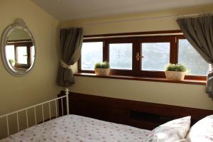a bedroom with windows and a bed and a mirror at Appartamento incantevole centrale e nel verde in Rivisondoli
