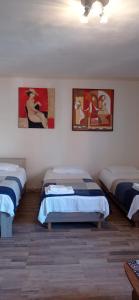 a room with three beds and paintings on the wall at Cozy studio in Hasselt in Hasselt