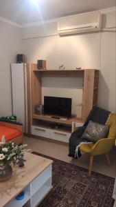sala de estar con TV, sofá y mesa en Quiet spacious apartment in Nafplio, en Nauplia