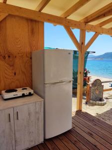 um frigorífico branco sentado num piso de madeira junto à praia em Camping Anamour em Torone