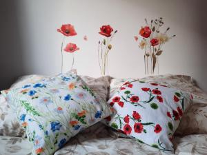 2 almohadas en una cama con flores en la pared en Apartament Bałtycka Sardynka en Ustka