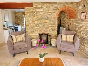 a living room with two chairs and a stone fireplace at David's Organic Farm Wales in Llanfallteg