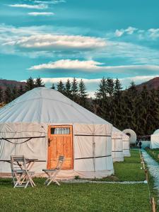 uma grande tenda com uma porta de madeira e uma cadeira em Glamping Iurte Mongole Spiritul Zimbrului em Vama Buzaului