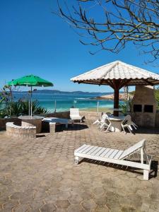 um pátio com uma mesa, cadeiras e um guarda-sol em Praia, Sol, luar e lazer em Itapema