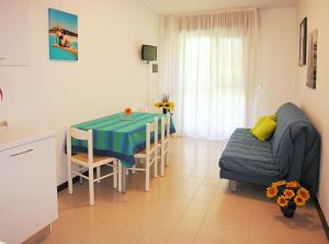 eine Küche und ein Wohnzimmer mit einem Tisch und einem Sofa in der Unterkunft Apartment Gemini con Piscina in Bibione