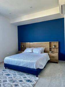 ein Schlafzimmer mit einer blauen Wand und einem großen Bett in der Unterkunft HERMOSA CABAÑA A POCOS MINUTOS DE BARRANQUILLA in Puerto Colombia