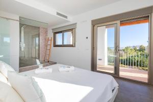 a bedroom with a white bed and a balcony at Villa in Ibiza Town sleeps 10 - Ses Llaneres in Ibiza Town