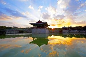 a chinese building in the middle of a pond at sunset at Gyeongju Bee House in Gyeongju