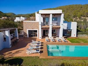 a villa with a swimming pool and lounge chairs at Villa in Ibiza Town sleeps 10 - Ses Llaneres in Ibiza Town