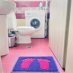 a bathroom with a toilet and a rug with pink shoes on it at LUNA'S HOUSE in Asprovalta