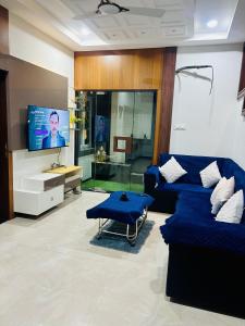 un salon avec un canapé bleu et une télévision dans l'établissement Villa adora, à Jodhpur