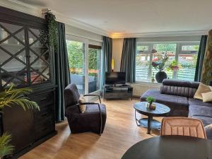 een woonkamer met een bank en een tv bij Bos chalet “relaxed” in Doornspijk