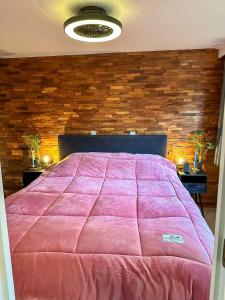 een slaapkamer met een groot roze bed met een bakstenen muur bij Bos chalet “relaxed” in Doornspijk