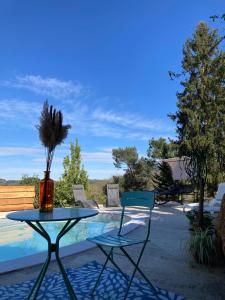 einen Tisch und zwei Stühle neben einem Pool in der Unterkunft Les hyacinthes 2 in Sarlat-la-Canéda