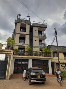 Nelly Apartments في Mbale: سيارة سوداء متوقفة أمام مبنى