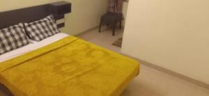 1 dormitorio con 1 cama con manta amarilla en The Grand Stays codissia, en Coimbatore