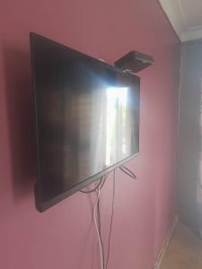 a flat screen tv hanging on a pink wall at Nelly Apartments in Mbale