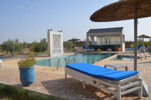 ein Pool mit einer blauen Bank und einem Sonnenschirm in der Unterkunft Urti Villa in Nzala
