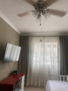 Schlafzimmer mit einem Deckenventilator, einem Bett und einem Fenster in der Unterkunft Apartamento térreo próximo ao Shopping Iguatemi in Votorantim