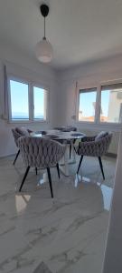 a room with two chairs and a table and windows at Ellis-Suites Nea Peramos Kavala in Nea Peramos