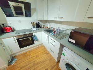 a kitchen with white cabinets and a sink and a dishwasher at F5 Near BARRY ISLAND PRIVATE AIRPORT Parking x 2 Cars Or Vans Free Wifi Washer Hob & Cooker Welcome Tray Provided in Barry