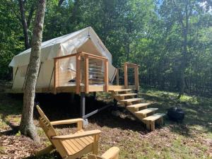 a tent with a staircase and chairs in a forest at Sweet Hill Glamping in Rhinebeck