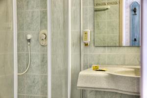 a bathroom with a shower and a sink and a mirror at Hotel am Markt Altentreptow in Altentreptow