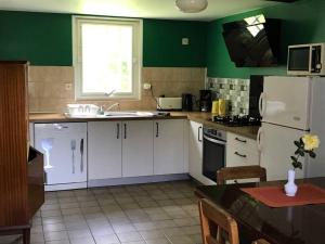 eine Küche mit weißen Schränken und einer grünen Wand in der Unterkunft Gîte au coeur de la campagne normande in Ouville
