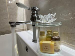a bathroom sink with a faucet and three bottles of honey at The Coach House in Chedworth